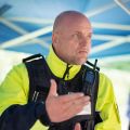 Gerd Buse, first chief superintendent and head of the Broichweiden highway patrol, is seen at a slight angle in the portrait. He gestures with his hand. He is wearing a neon yellow and dark blue uniform.