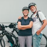 Zwei Senioren mit Fahrradhelm stehen vor zwei E-Bikes