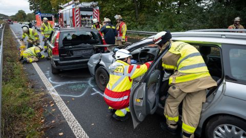 Firefighters stabilize two accident vehicles with a pole block system. Other firefighters and vehicles can be seen in the background.